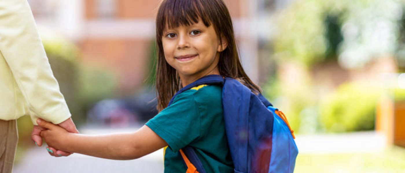 Young girl wearing a backpack and holding her mother's hand