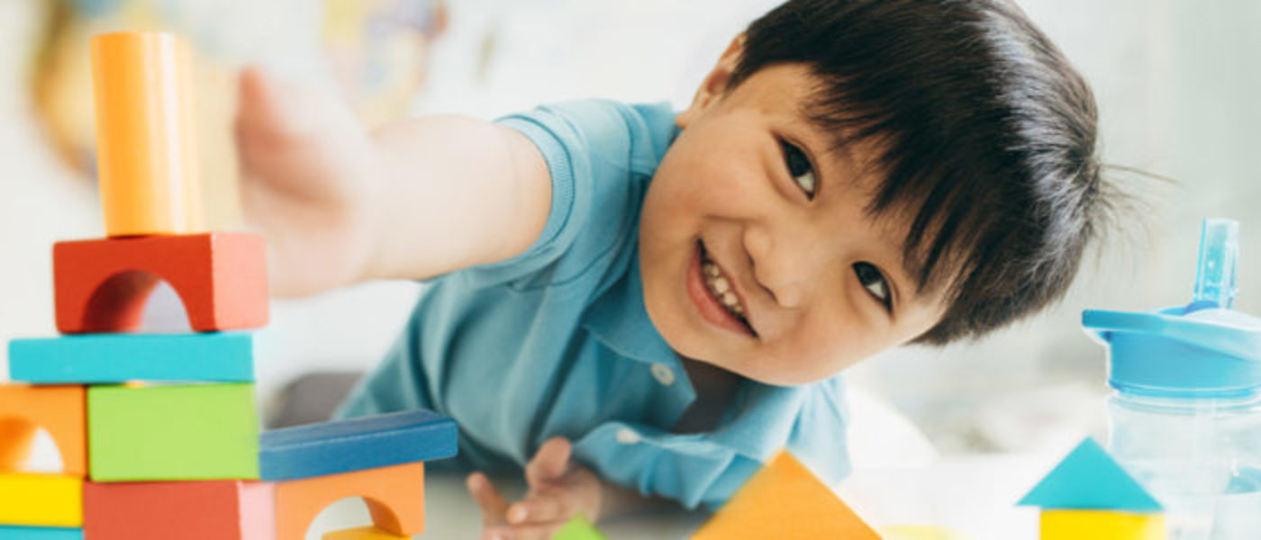 Young boy builds a tower with colorful wooden blocks