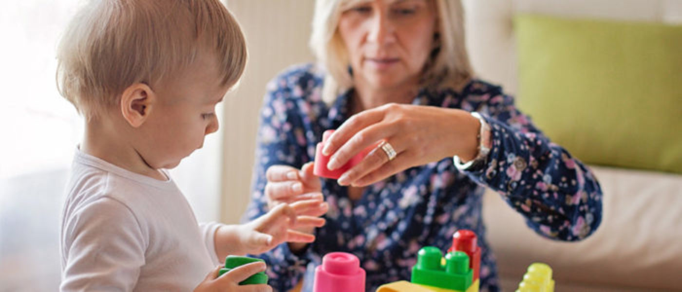 Female caregiver building legos with young child