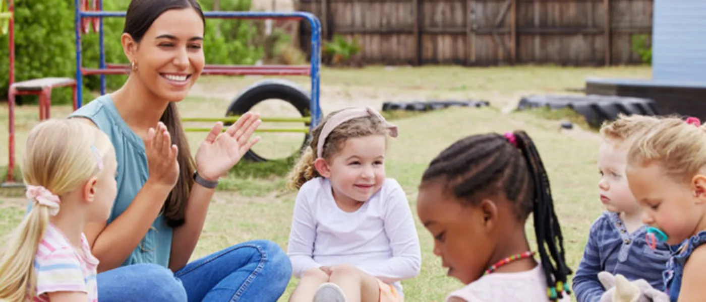 Young children and their teacher sitting in a circle outdoors